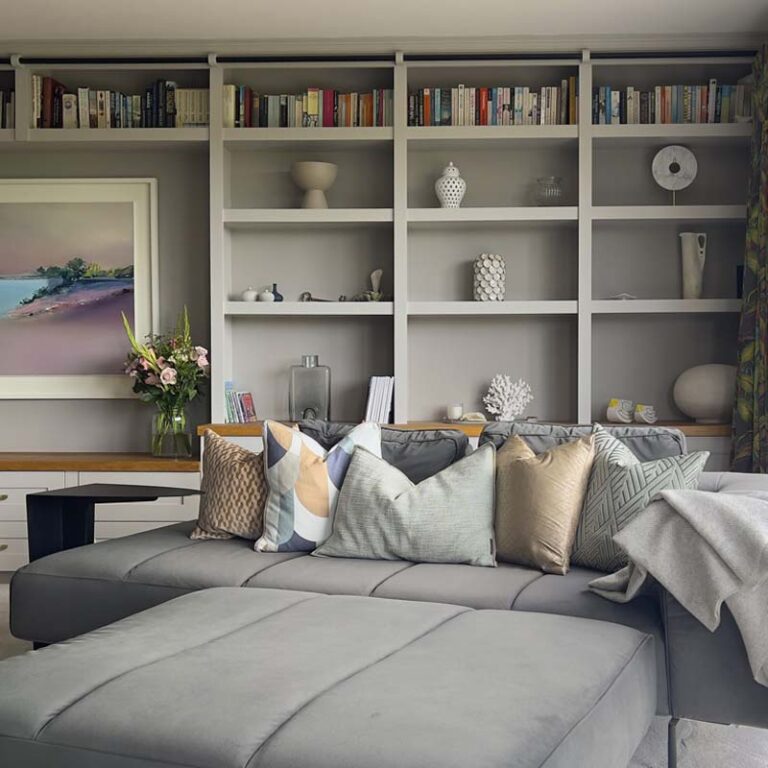 Library wall detail with decorative elements and a dark grey velvet modern sofa in a contemporary Sneyd Park home by Ivywell Interiors