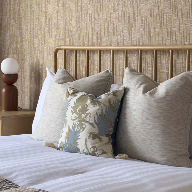 Detail of cushions and wallpaper behind the headboard in a Bedminster family townhouse bedroom by Ivywell Interiors