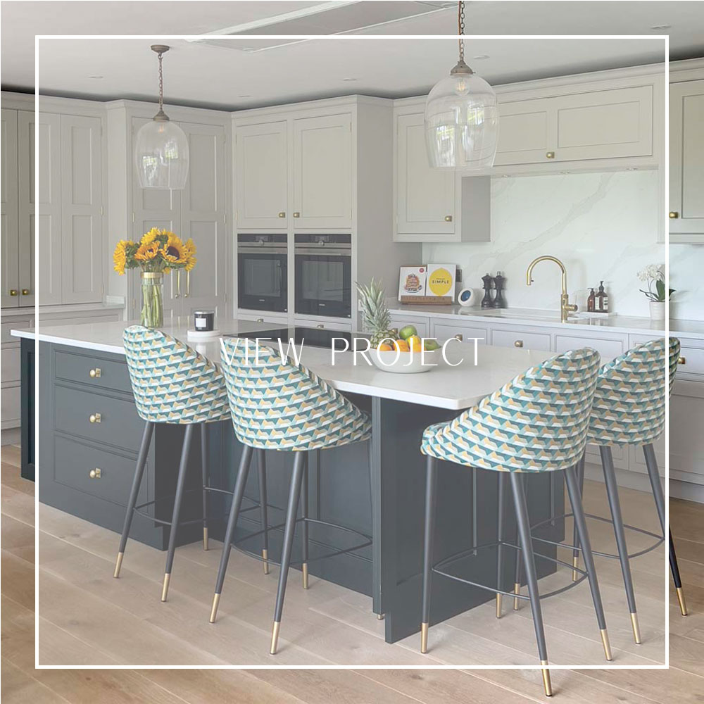 Shaker-style kitchen with large dark blue island, colourful upholstered stools, and brass detailing in a contemporary Sneyd Park family home by Ivywell Interiors