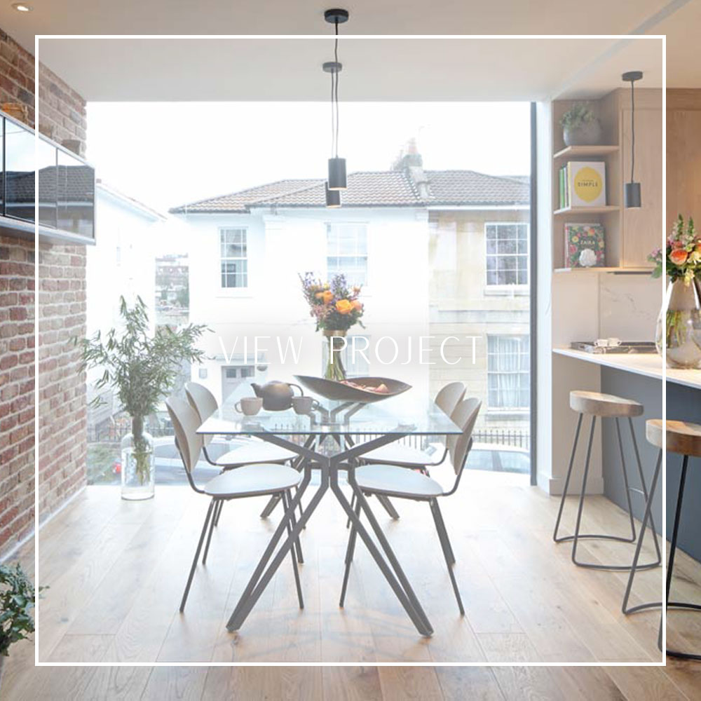 Open-plan dining room with exposed red brick wall and floor-to-ceiling profile-less window in a new-build home in Cotham by Ivywell Interiors