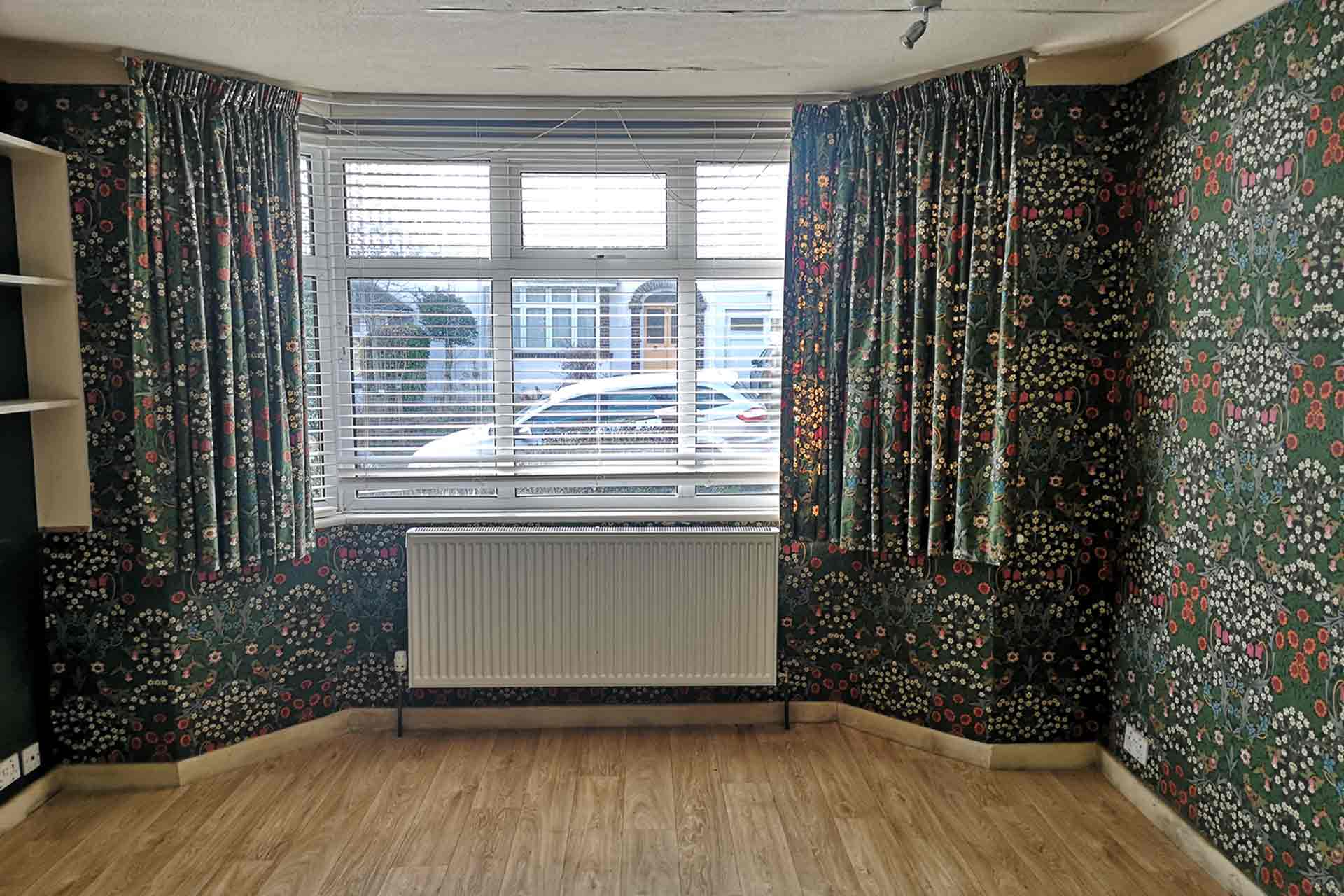 Living room before renovation with William Morris wallpaper and matching curtains—dated interior typical of 1950s homes in need of modernisation
