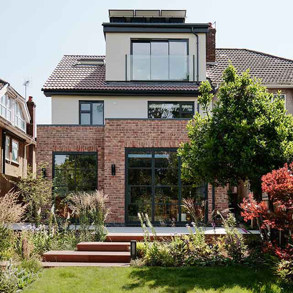 Rear exterior of renovated 1950s Redland home featuring brick extension, black-framed glazing, and landscaped garden by Ivywell Interiors