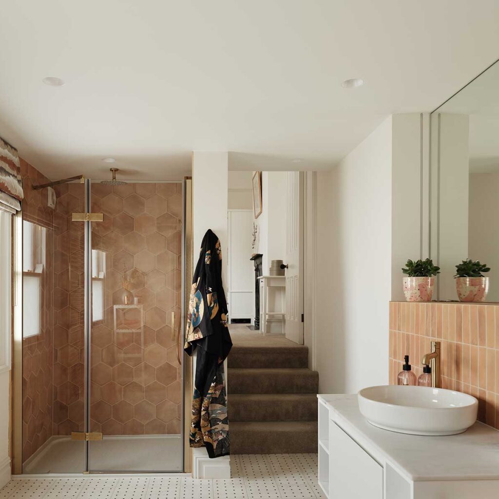 shower room with terracotta hexagonal tiles in the shower, brass fixtings, and large white vanity unit